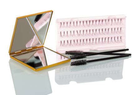 A set of false eyelashes bunches, a brush for applying mascara and a mirror isolated on white background.の写真素材