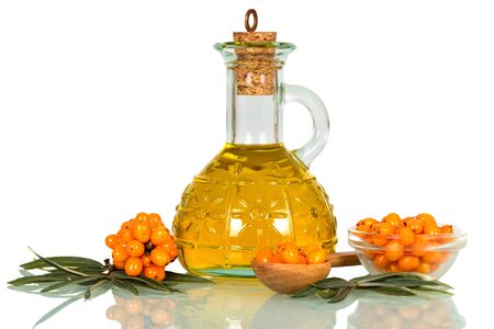Branches with berries of sea buckthorn, berries in a wooden spoon and a bottle of oil isolated on white background.の写真素材