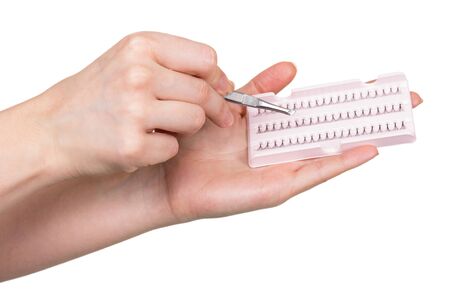 Set of false eyelashes bunches and tweezers in female hands isolated on white background.の写真素材
