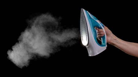 Iron with steam in female hand, isolated on black backgroundの写真素材
