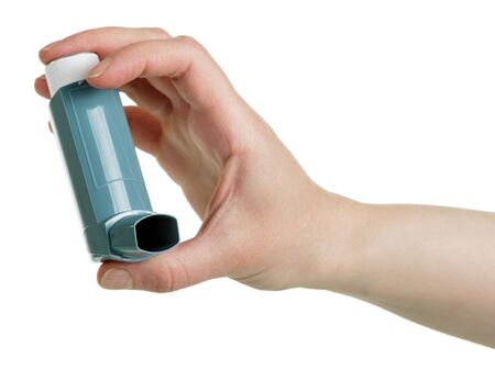 Asthma inhaler in female hand isolated on a white background.の写真素材
