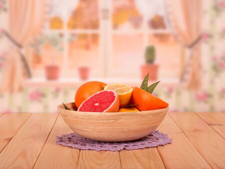 Whole and cut grapefruits, lemons and oranges with leaves in a bowl on the background of the kitchen.の写真素材