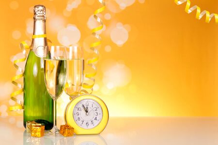 Waiting for the holiday, bottle of champagne and clock on  table backgroundの写真素材