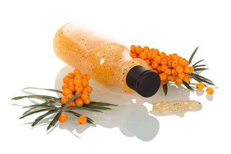Branches with sea buckthorn berries and bottle with a face scrub isolated on white background.の写真素材
