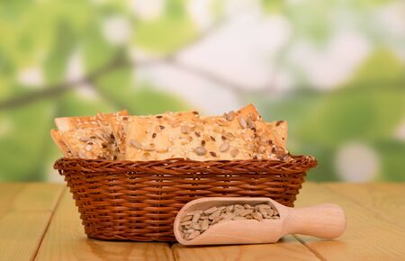 Basket with crispy biscuits and a wooden scoop with fried sunflower seeds on an abstract green background.の写真素材