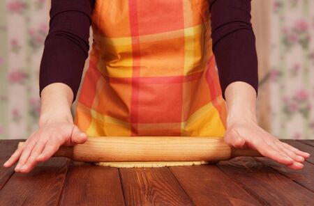 Woman forms a layer of dough  on wooden tableの写真素材
