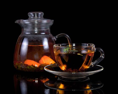 Cup of hot tea with a saucer and jug isolated on black backgroundの写真素材