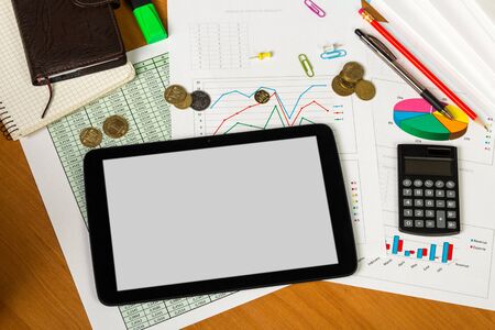 Tablet, calculator, notebooks, pen and pencil, sheets of paper with the accounts and diagrams, small money on the desktop background.の写真素材