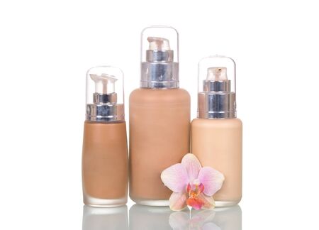 Bottles with foundation of various tones and an orchid flower isolated on white background.の写真素材