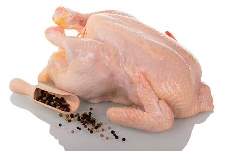 A whole raw chicken carcass, a scoop with various peppers and scattered isolated on white background.の写真素材