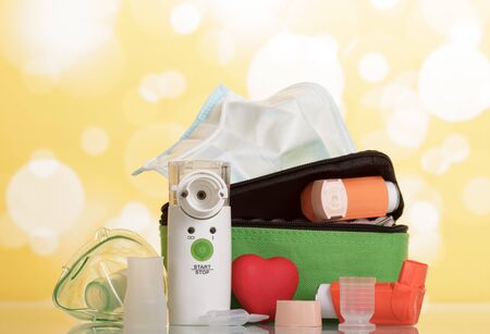 Electronic mesh inhaler with child's mask and other devices on yellow backgroundの写真素材