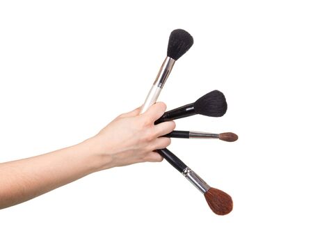 Four cosmetic brushes in a female hand isolated on a white background.の写真素材