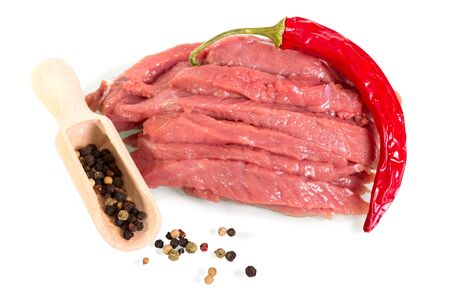 Pieces of raw beef, spicy red pepper and scoop with different round peppers isolated on white background.の写真素材