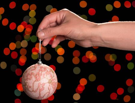 New Year's toy-ball with decorations in female hand on flickering backgroundの写真素材