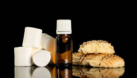 Bottle with a flavored liquid for smoking electronic cigarette, and sweets isolated on black backgroundの写真素材