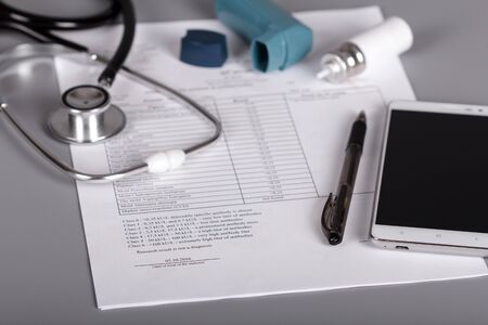 Medical phonendoscope, an inhaler and sheet of doctor appointments, on gray backgroundの写真素材