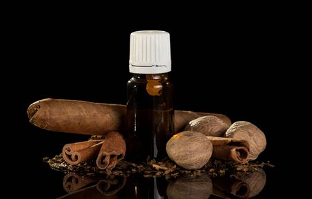 Cigar and bottle with liquid for smoking with the smell of spices isolated on black backgroundの写真素材