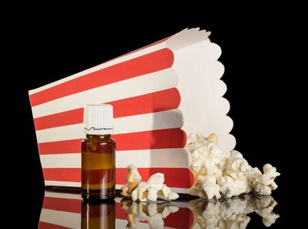 Aromatic liquid for smoking an electronic cigarette, and box of popcorn isolated on black backgroundの写真素材