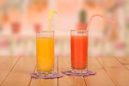Two glasses of fresh orange and grapefruit juices, straws on the kitchen background.の写真素材