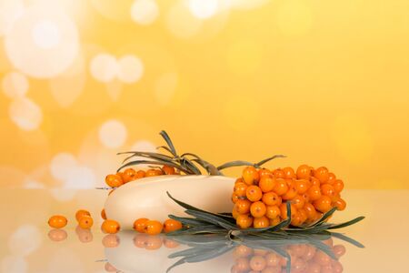 Branch with berries of sea buckthorn and soap closeup on abstract yellow background.の写真素材