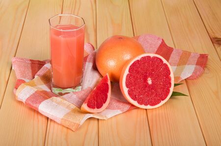 Grapefruits and glass of juice on wooden tableの写真素材