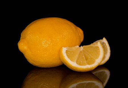 Whole lemon and chopped slices isolated on black backgroundの写真素材