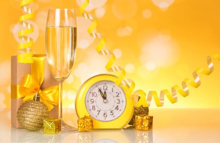 Wine glass with champagne, presents and watches on bright sparkling backgroundの写真素材