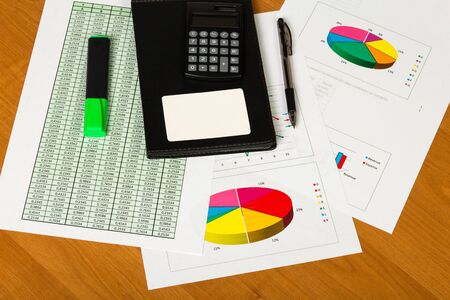 Notepad, calculator, blank card, pen and marker, sheets of paper account and charts on the desktop background.の写真素材