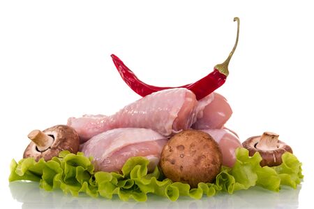 Raw chicken legs, champignons, hot peppers and lettuce leaves isolated on white background.の写真素材