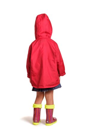Girl is back in rubber boots and a raincoat isolated on white backgroundの写真素材