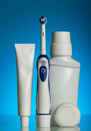 Electric brush, toothpaste, rinse and thread on blue backgroundの写真素材