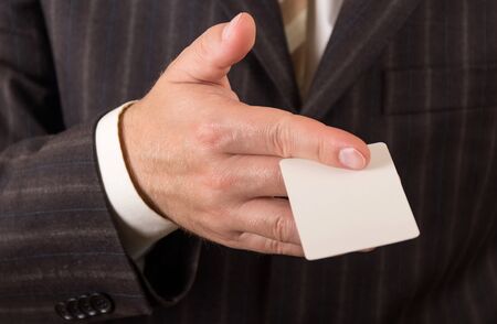 Businessman in suit with business white card, close-upの写真素材