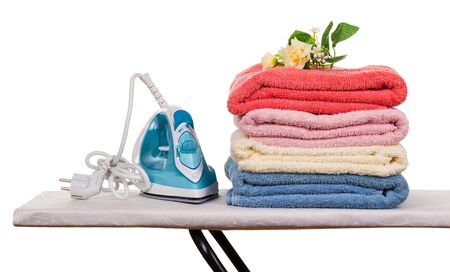 Electric iron and pile of clean Terry towels on Ironing Board, isolated on white backgroundの写真素材