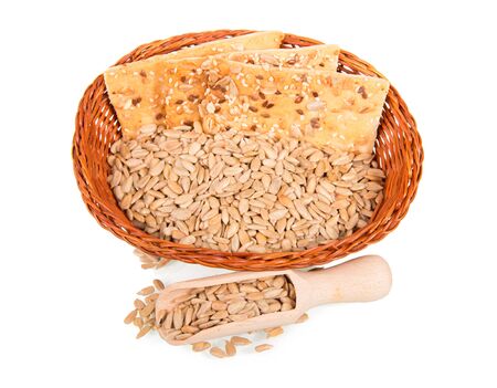 Whole-grain breads and sunflower seeds in wicker basket, wooden scoop, isolated on white backgroundの写真素材