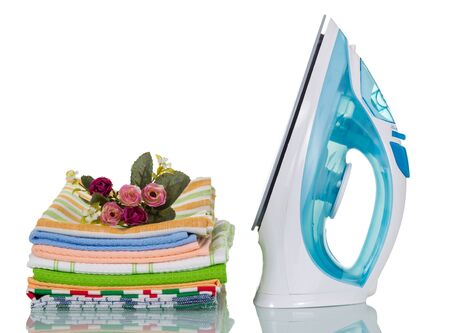 Electric iron and ironed stack of kitchen towels isolated on white backgroundの写真素材