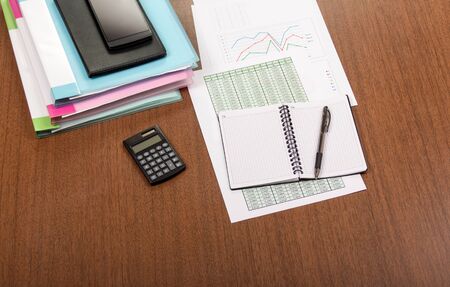 Folders with documents, charts, reports, calculator and pen on a desktop in officeの写真素材
