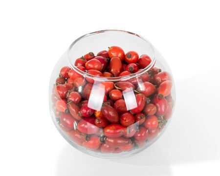 Red berries of briar in large glass bowl, isolated on whiteの写真素材