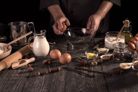 Set of products and flavors for dessert, hands of pastry chef at work isolated on black backgroundの写真素材