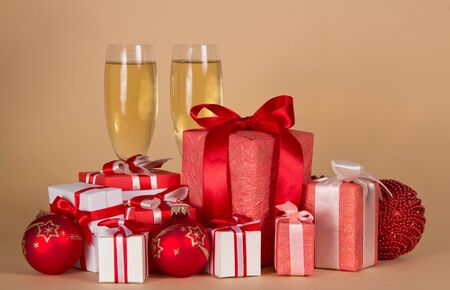 lot of Christmas gifts in different beautiful boxes, glasses of champagne, on beige backgroundの写真素材