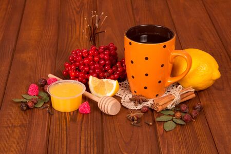 Cup of tea from the berries of viburnum with honey, lemon and spices on brown wooden tableの写真素材