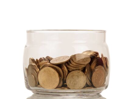 Bunch of coins of different denominations in glass jar isolated on white backgroundの写真素材