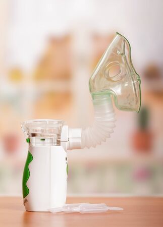 Ultrasonic membrane-mesh nebulizer mask, vials of medicine on background of tableの写真素材