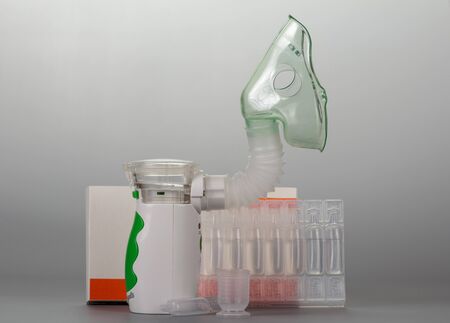 Modern mesh-nebulizer, box of vials and beaker on gray backgroundの写真素材