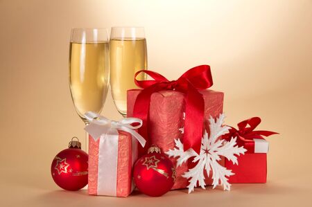Two glasses with champagne, Christmas gifts, decorations and snowflake on a beige backgroundの写真素材