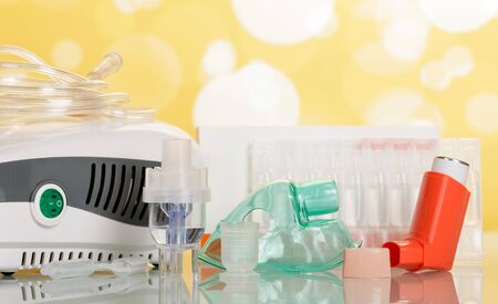 Two types of inhalation devices, children's mask and liquid for inhalation, on light yellow backgroundの写真素材
