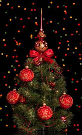 Shimmering Christmas tree with toys gifts and beads isolated on black backgroundの写真素材