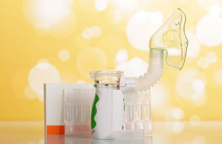 Electronic mesh nebulizer with pediatric mask, box of spare vials, on yellow backgroundの写真素材