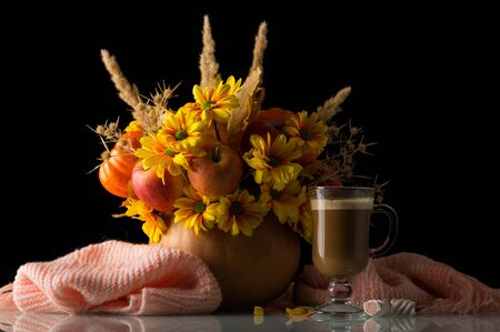 Original autumn composition in pumpkin, nearby Cup of cappuccino and warm scarf isolated on black backgroundの写真素材