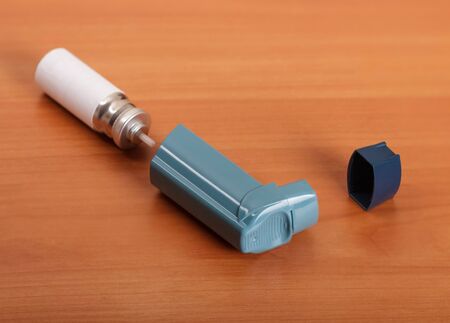 Small inhaler and cap, dispenser of medicine, on brown wooden surfaceの写真素材