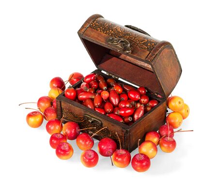 Wooden box filled with berries of wild rose, next to scattered small apples isolated on white backgroundの写真素材